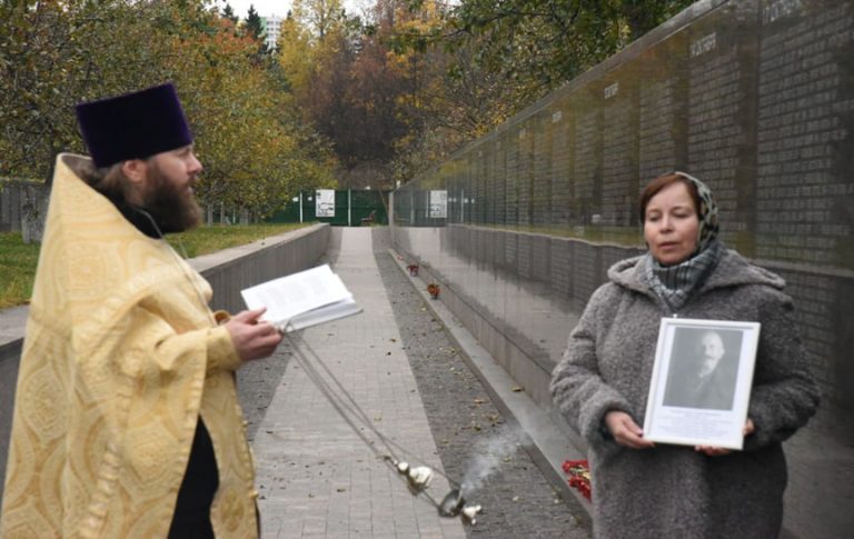 Иллюстрация 14. Клирик Климентовского храма (2022-2024) священник Александр Морозов служит панихиду на церковно-общественном мемориальном комплексе «Бутовский полигон» по уб. старосте Спасского храма, генерал-майоре Александре Ивановиче Беляеве. Прихожанка Спасской общины на Большой Спасской Елена Анатольевна Кайнова с фотографией старосты утраченного Спасского храма А. И. Беляева. 21 октября 2022 года.